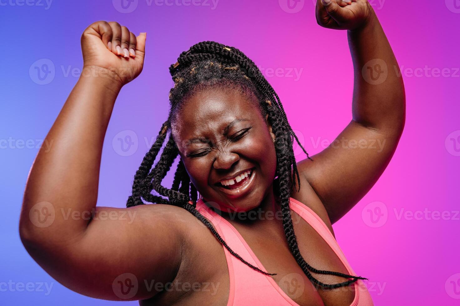 Joyful African plus size woman in sportswear gesturing and smiling on vibrant background photo