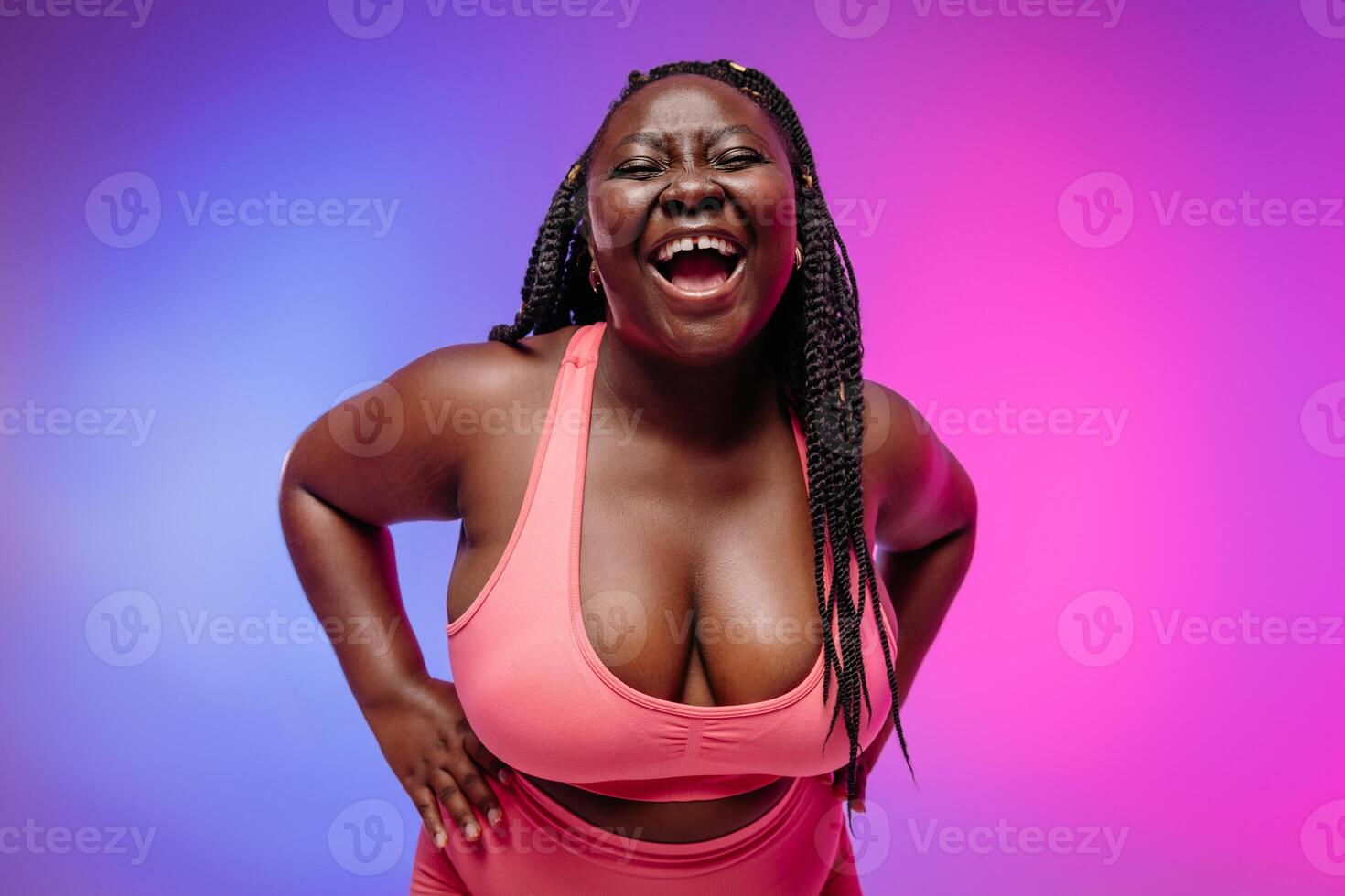 Beautiful African curvy woman in sportswear holding hands on hip and radiating self-love on vibrant background photo