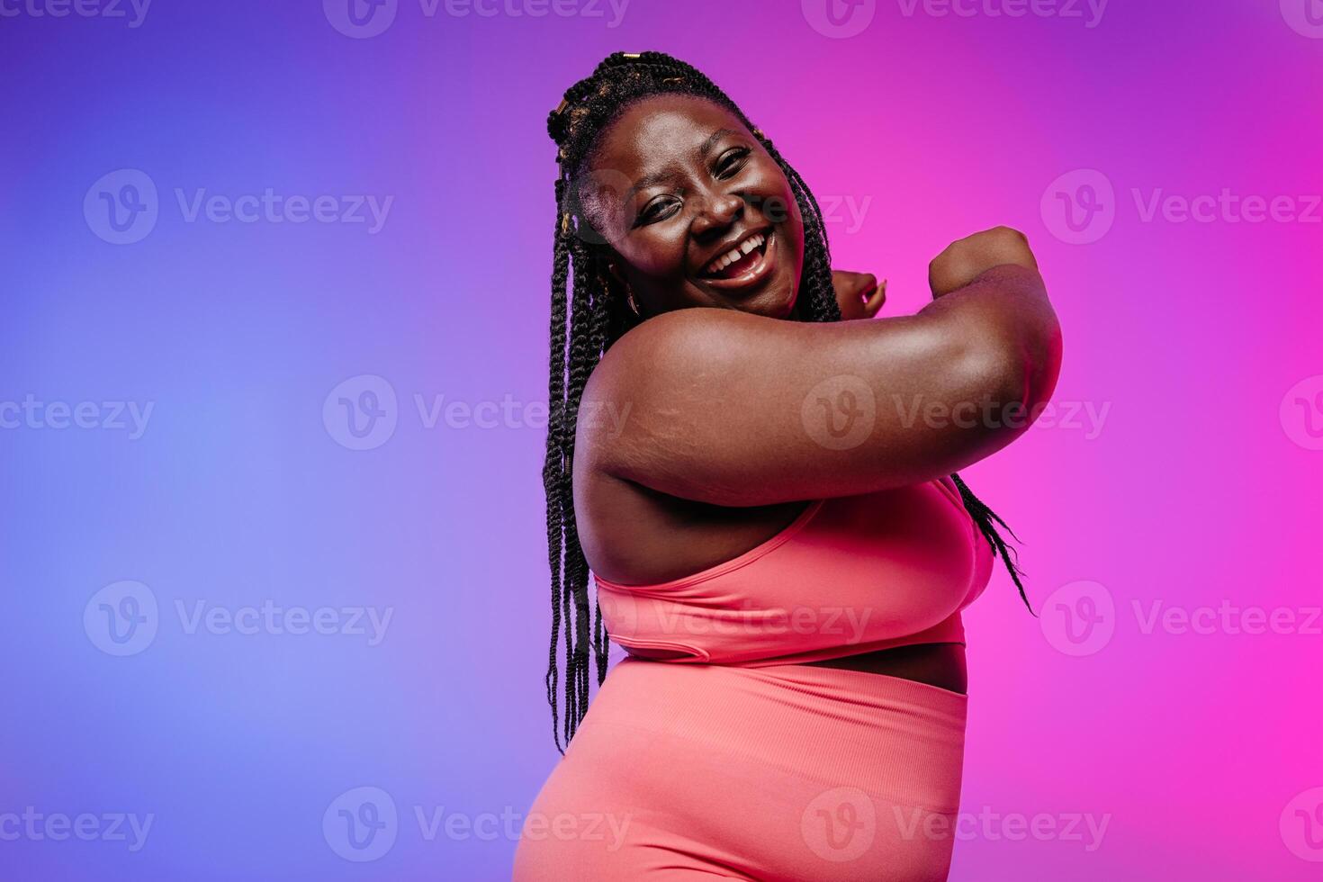 Voluptuous African woman in sportswear gesturing and smiling against vibrant background photo