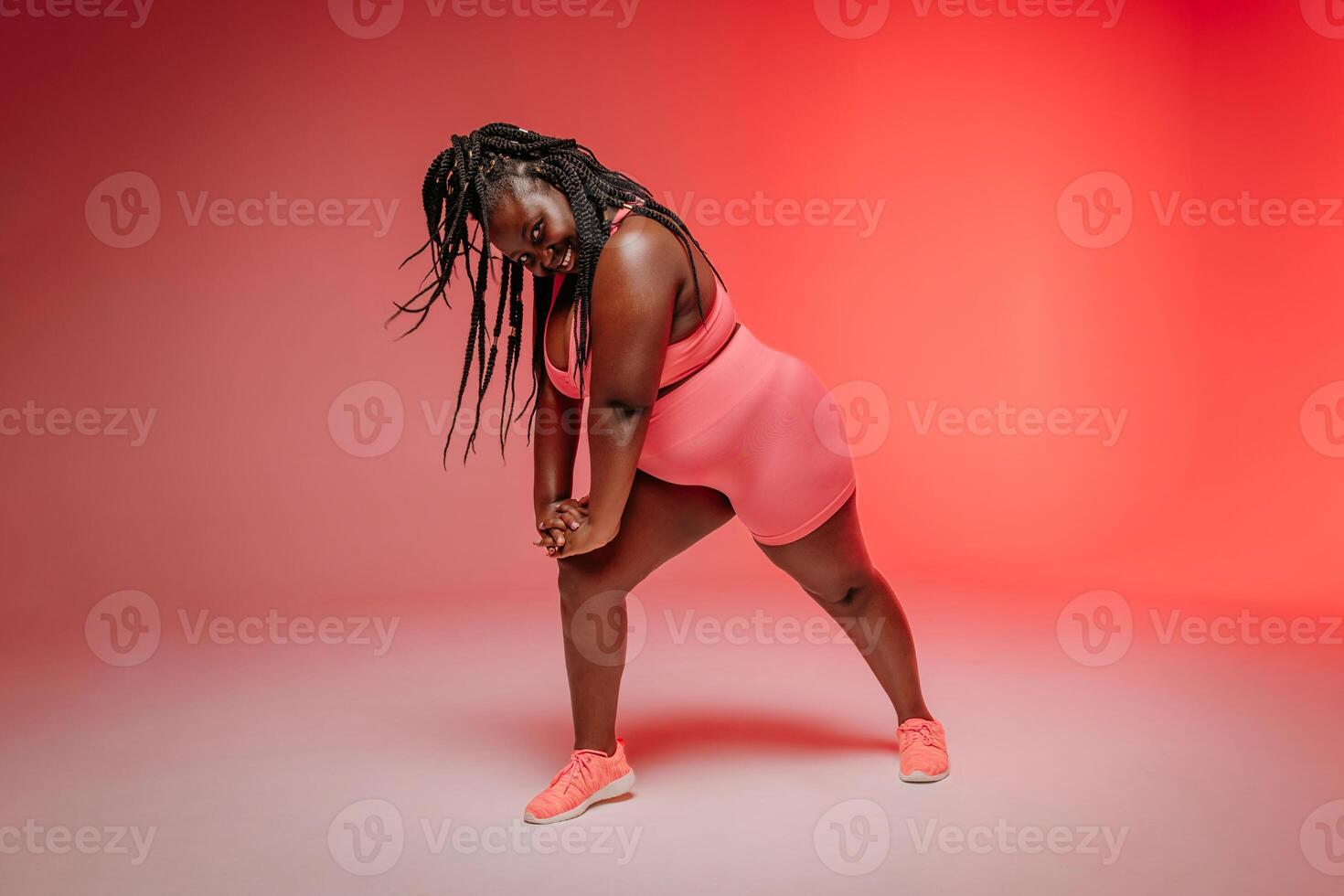 Happy plus size woman in sportswear exercising and looking confident on colorful background photo