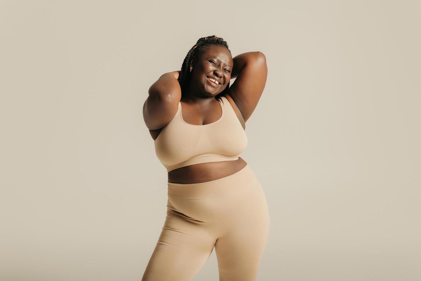Joyful African plus size woman in underwear radiating love to her body on studio background photo