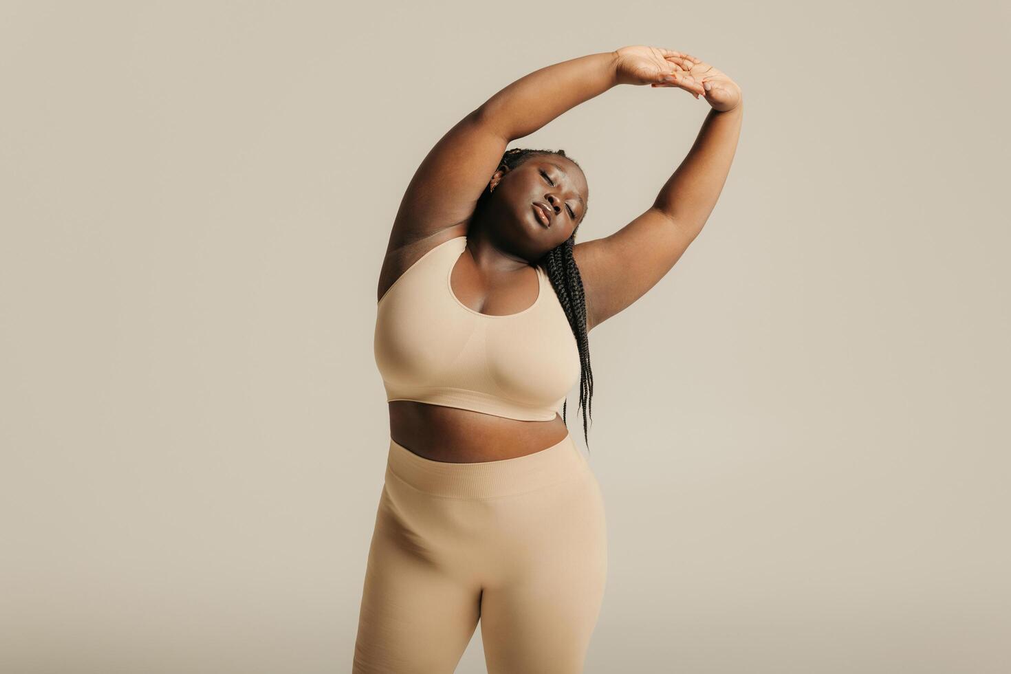 Attractive African plus size woman in underwear radiating self-love while standing on studio background photo