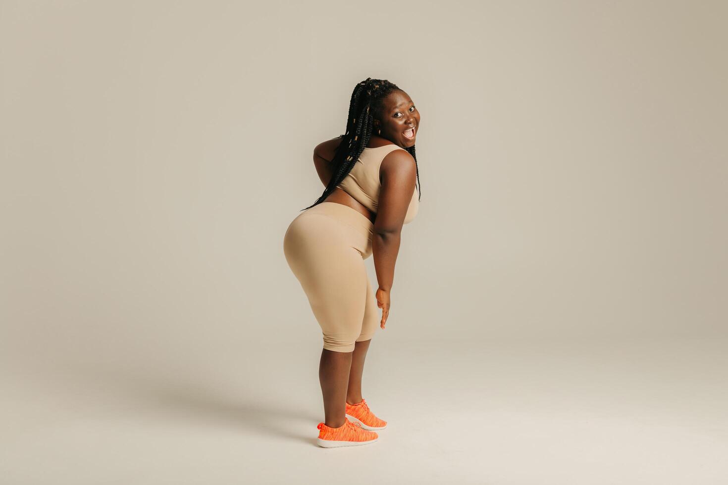 Beautiful curvy African woman in sportswear looking happy and confident while standing on studio background photo