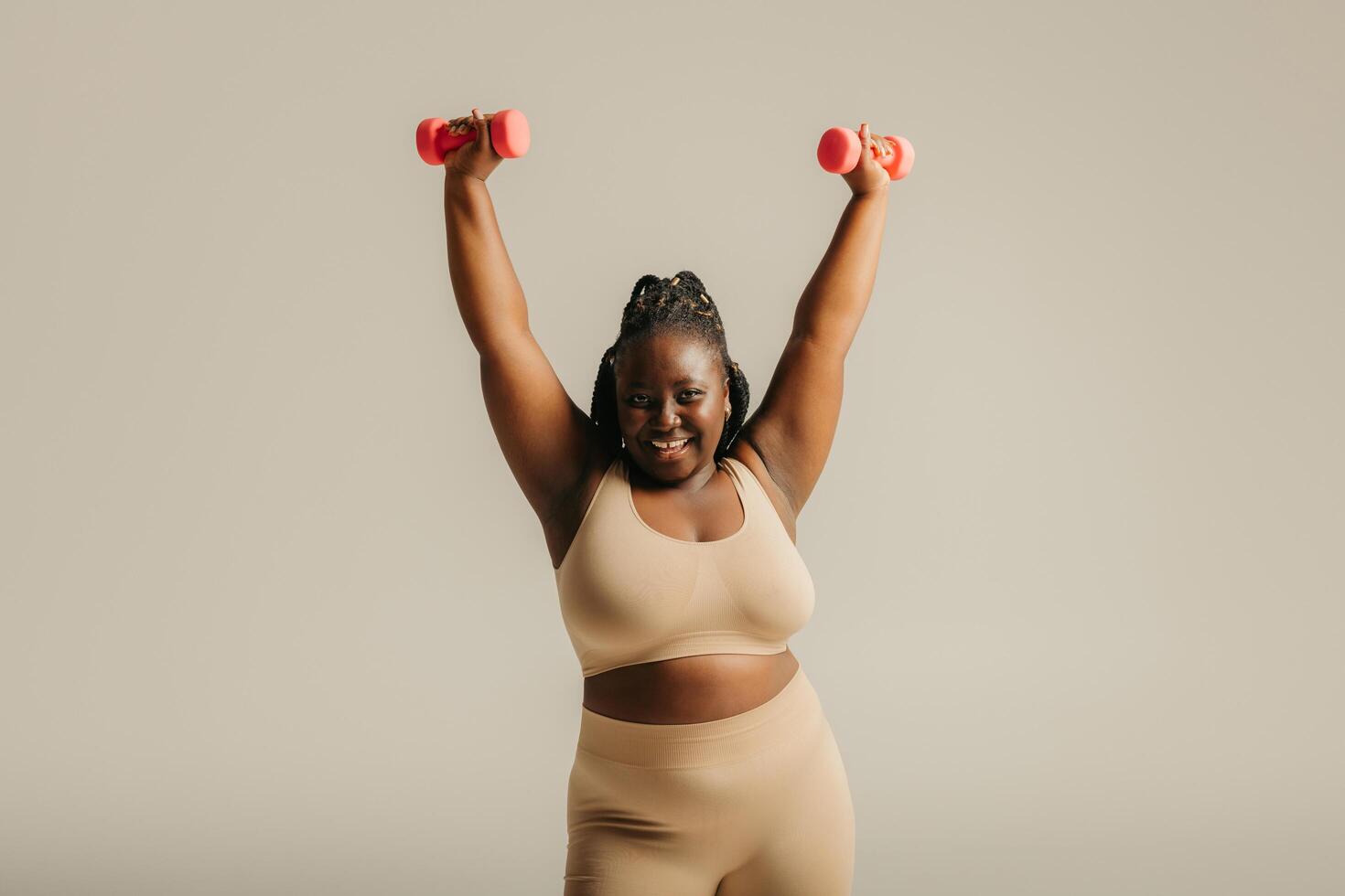 Beautiful curvy African woman in sportswear radiating confidence while exercising on studio background photo