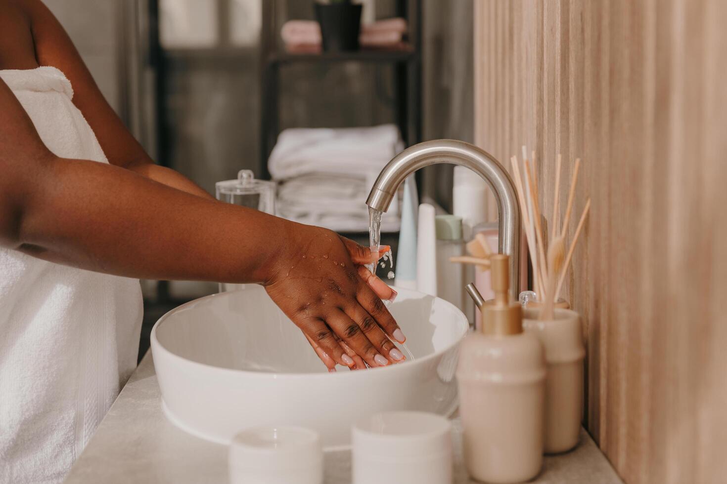 Close-up of plus size African woman covered in towel washing hands at the domestic bathroom photo