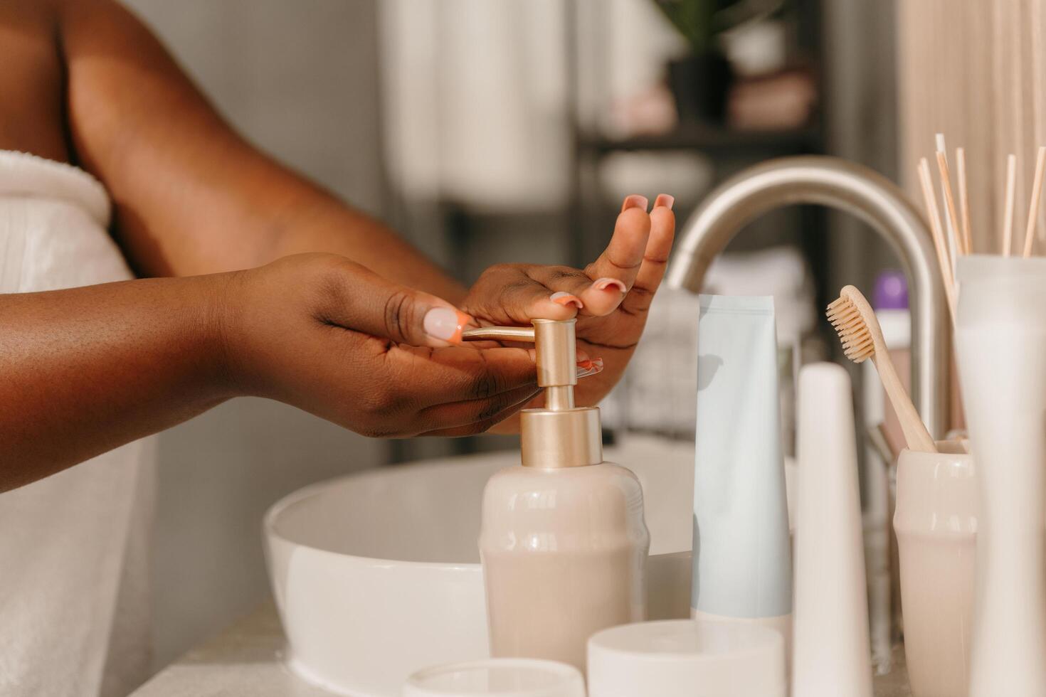 Close-up of curvy African woman covered in towel washing hands with soft soap in bathroom photo