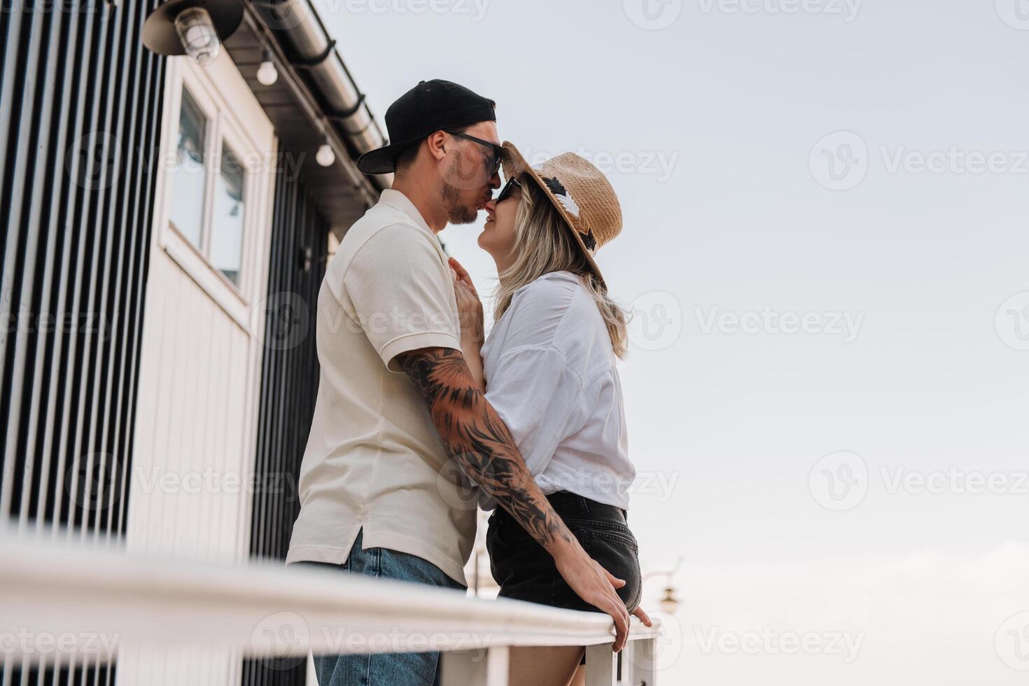 Beautiful romantic couple embracing and kissing while spending time on the house terrace together photo
