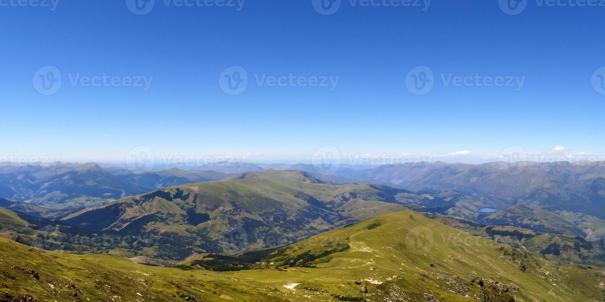 Majestic mountain landscape with clear blue sky and rolling green hills photo
