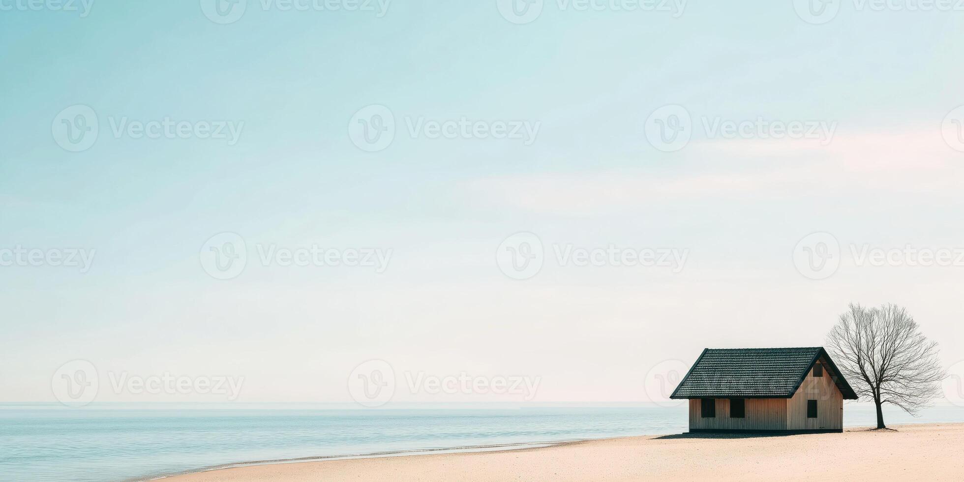 Solitary beach hut by tranquil sea with clear sky and bare tree photo
