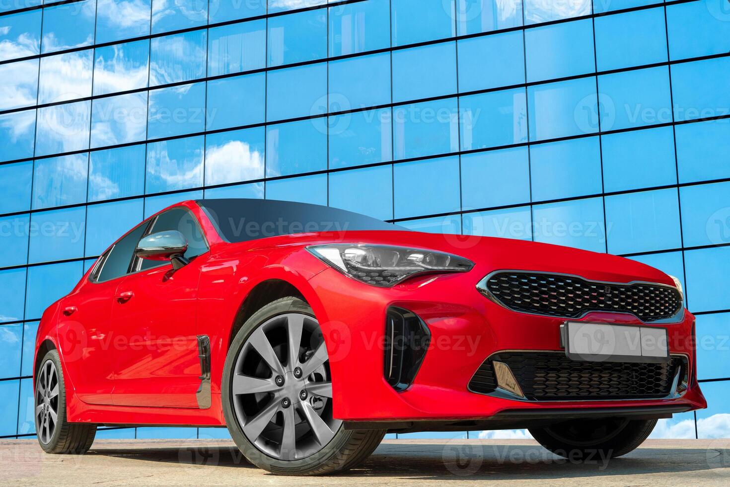 Red car on a background of a mirrored wall of a house with clouds reflections. Stylish, modern, bright image of the car for design solutions. photo