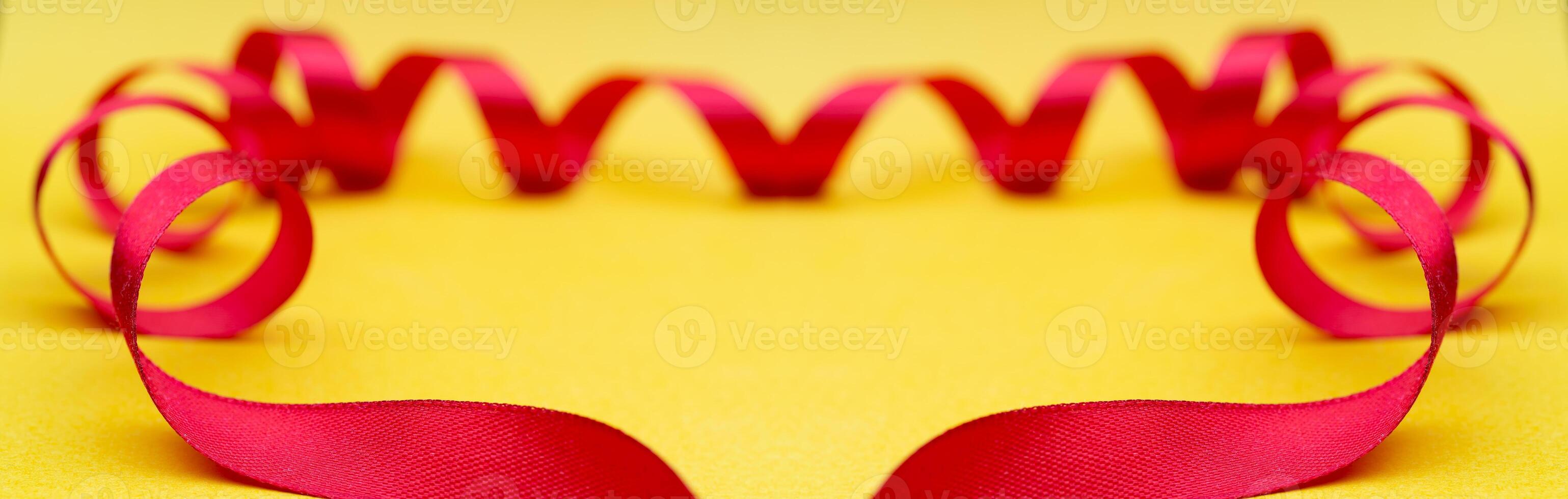 Frame of red ribbon on yellow background. Festive substrate for holiday invitation. photo
