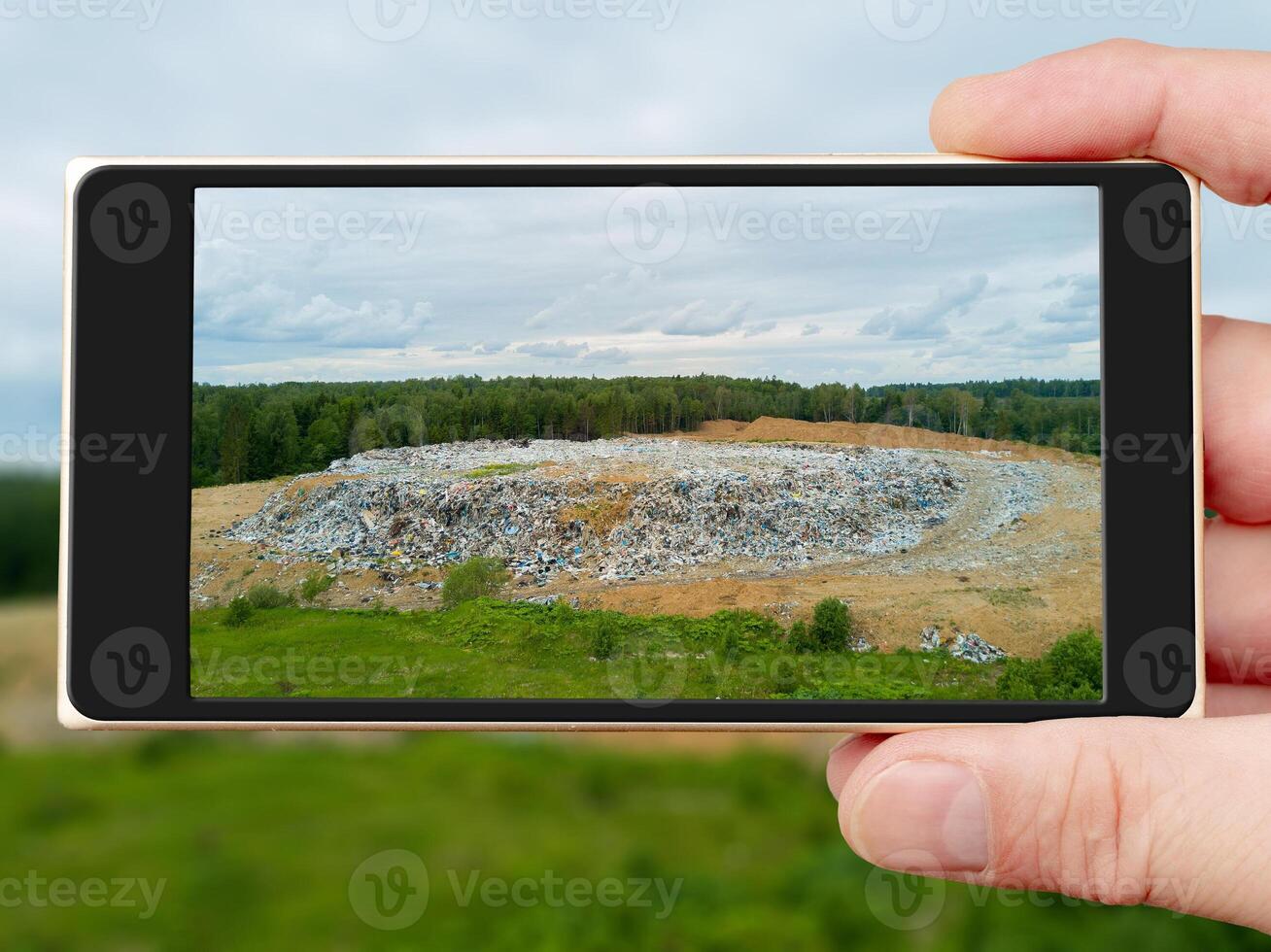 Garbage dump on smartphone screen. Polluting landfill in the forest. Problems of environmental pollution. photo