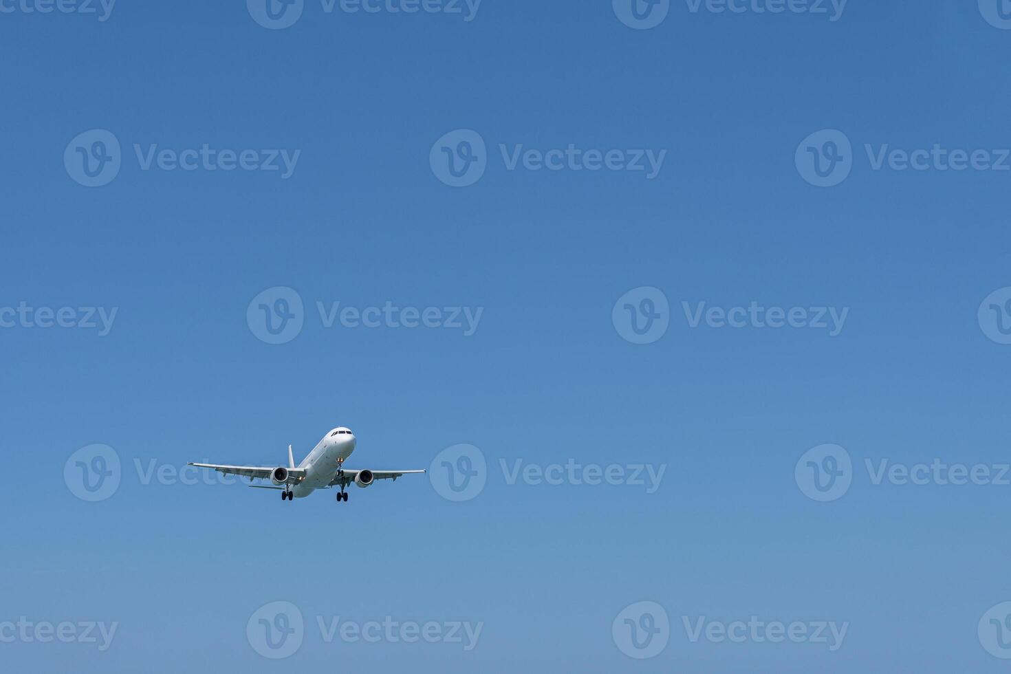 An approaching plane in the empty blue sky. A large expanse of empty sky. photo