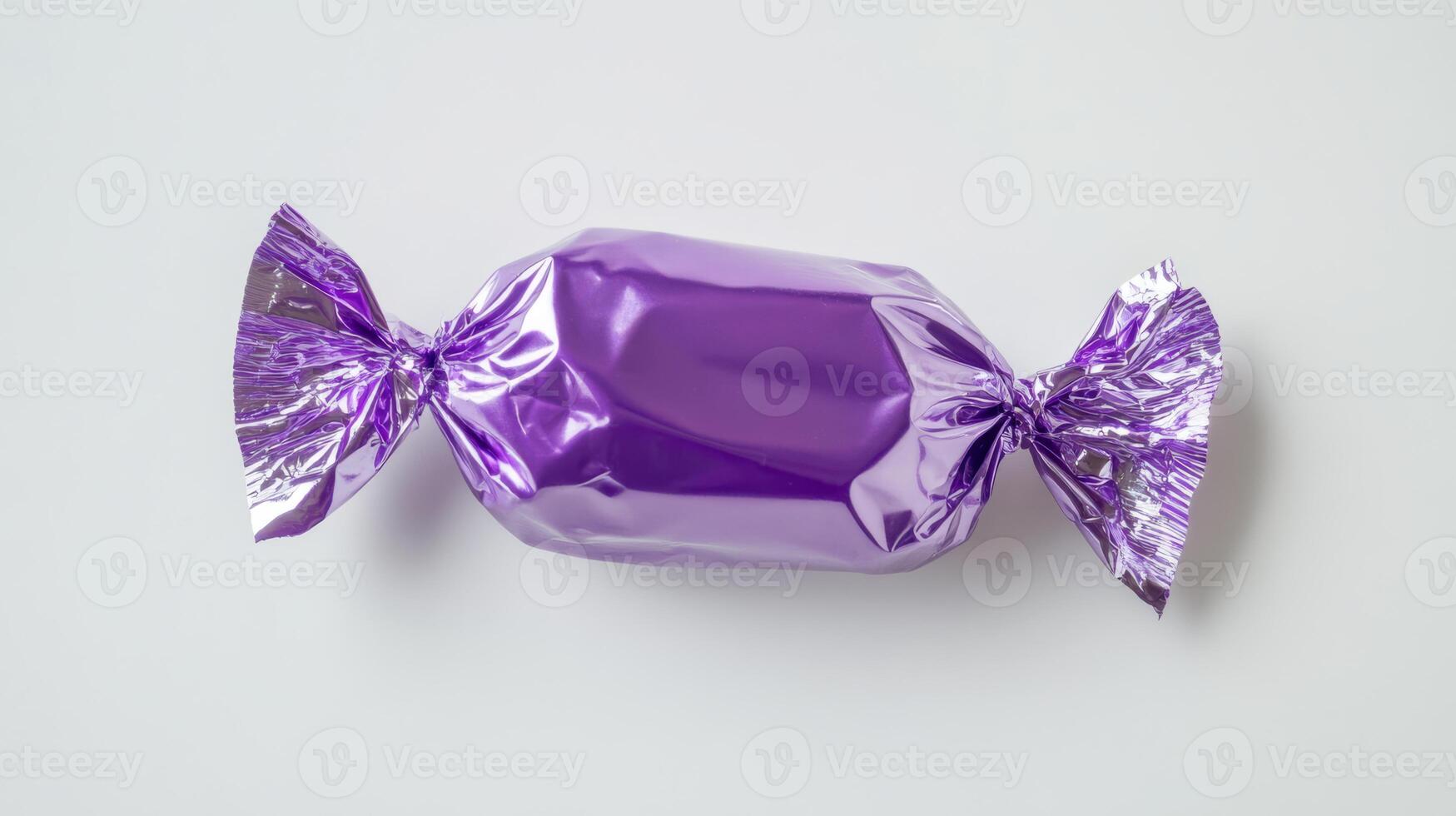 A shiny purple candy, wrapped in vibrant foil, stands out against a clean background. This image is ideal for showcasing sweet treats and designing appealing confectionery products photo