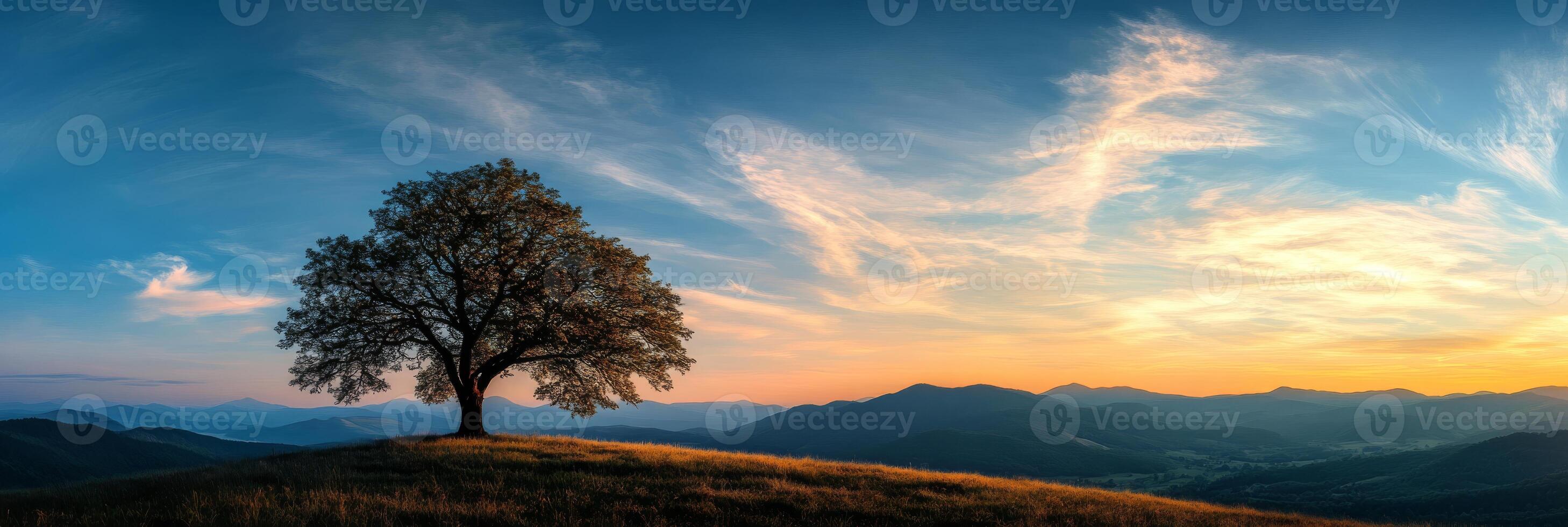 In a serene landscape, a lone tree silhouette stands against a stunning sunset and majestic mountains, creating a colorful sky that evokes a deep sense of peace in natures beauty photo