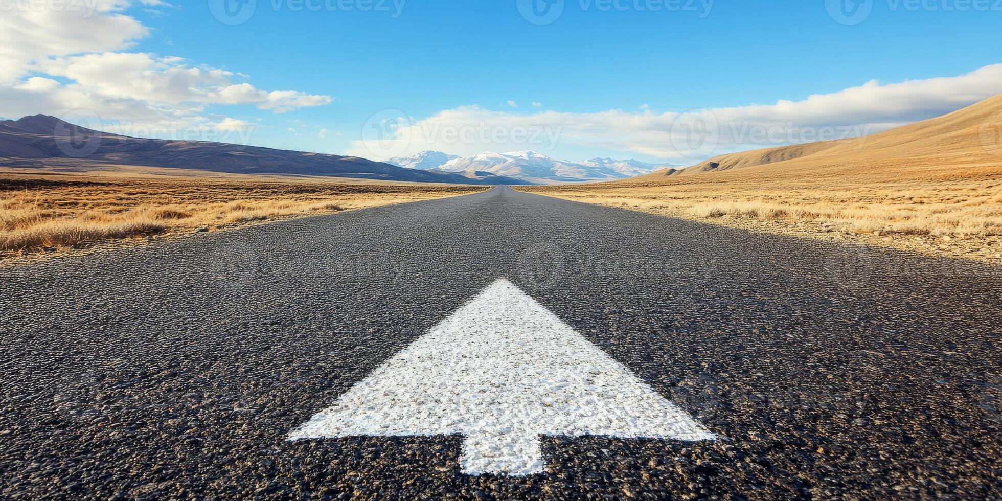 An expansive asphalt road stretches boldly ahead, marked by a prominent arrow pointing forward, representing the journey of direction, growth, and endless possibilities that lie on a clear horizon photo