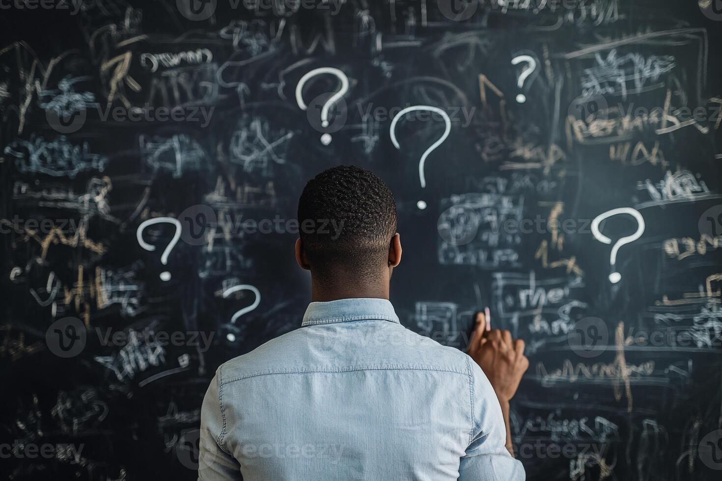 A man stands in front of a chaotic blackboard filled with question marks and scribbles, reflecting on his business strategy and the challenges ahead in his entrepreneurial journey to success photo
