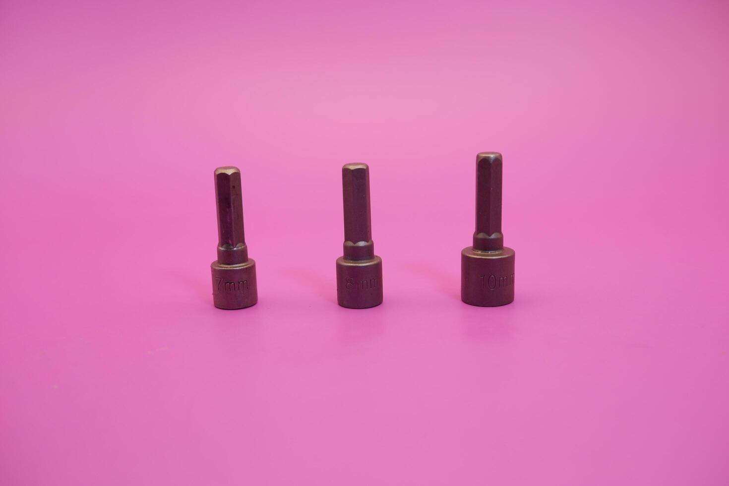 Hexagon screwdriver bit sockets measuring 7 mm, 8 mm, and 10 mm isolated on purple background. photo
