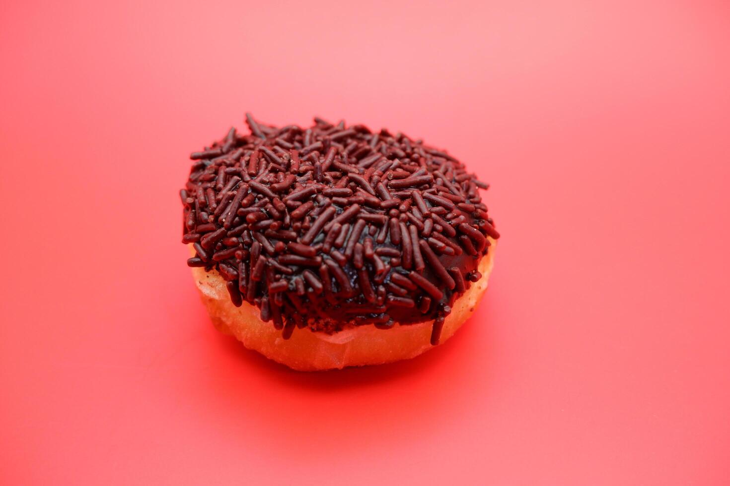 donut with chocolate sprinkle isolated on red background photo