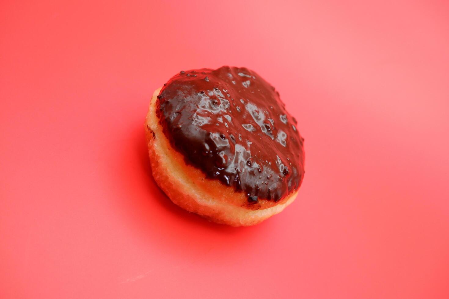 donut cake with chocolate topping on top. donut cake isolated on red background. photo