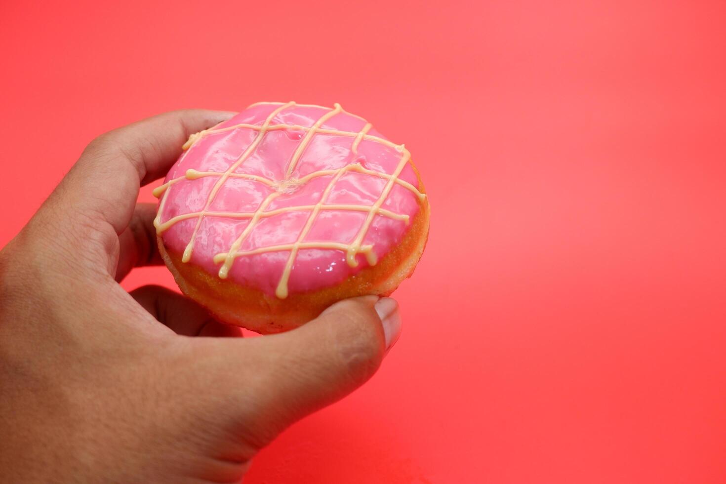 hand holding donut cake isolated on red background. photo