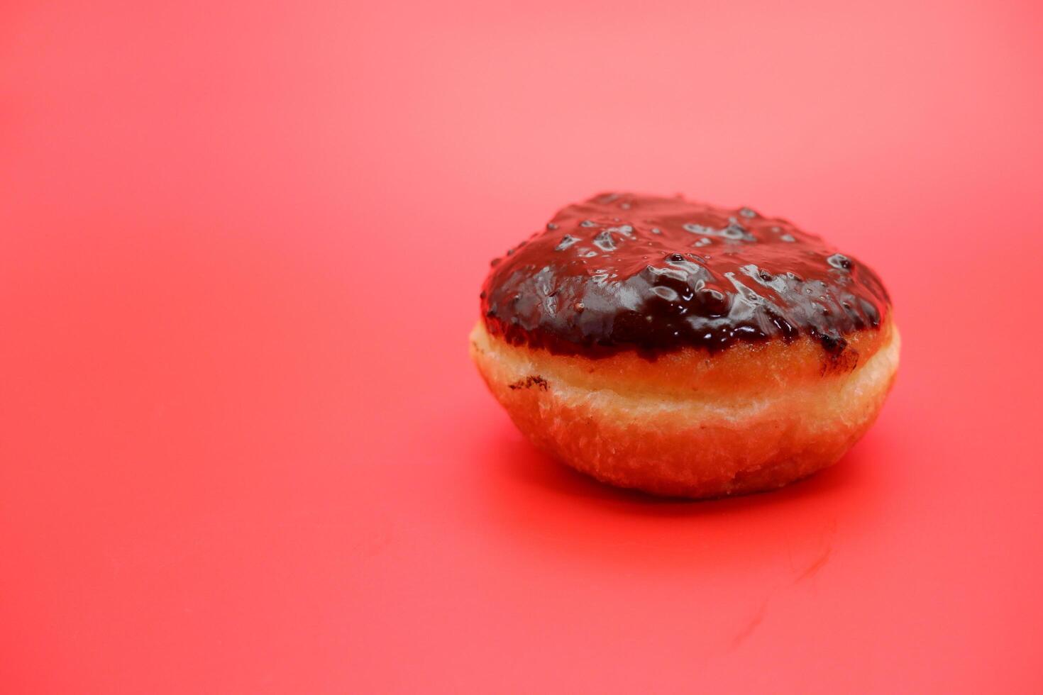 donut cake with chocolate topping on top. donut cake isolated on red background. photo