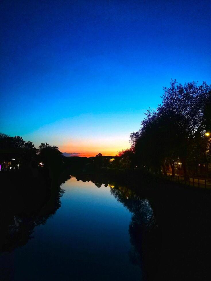 SILHOUETTE OF A CITY RIVER AT SUNDOWN photo