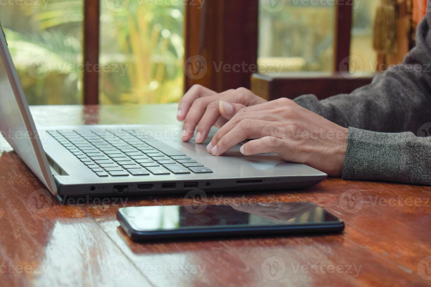 Close up side view young man typing with laptop on table in livingroom, remote working. Digital nomand photo