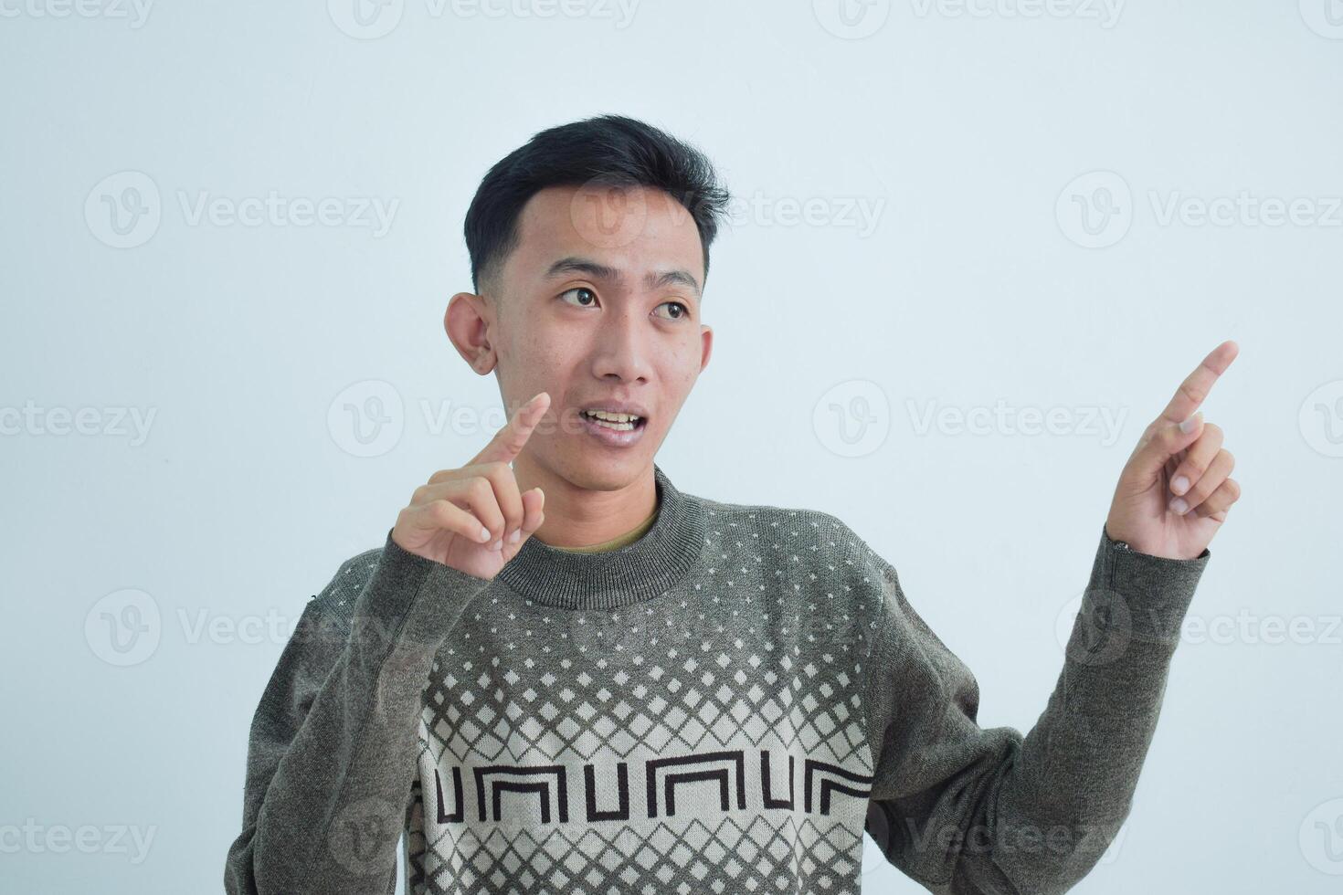 Asian young man showing pointing gesture with gesture and expression. Isolated on white background photo