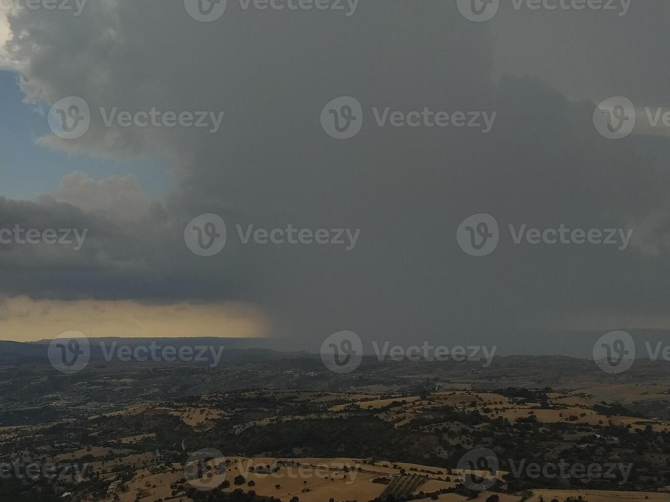 Storm front on the rolling hills, a clash between the forces of nature. Dark skies loom over the sunlit landscape. photo