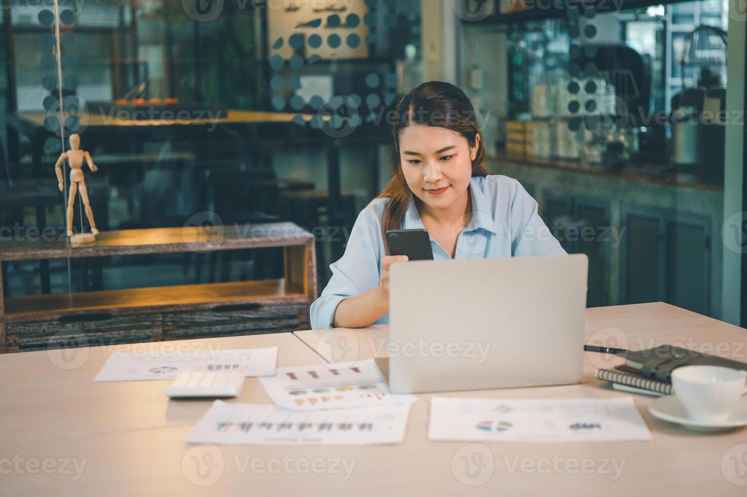 Business asian woman sitting at her desk with laptop using mobile phone during checking an email or social media on internet. photo
