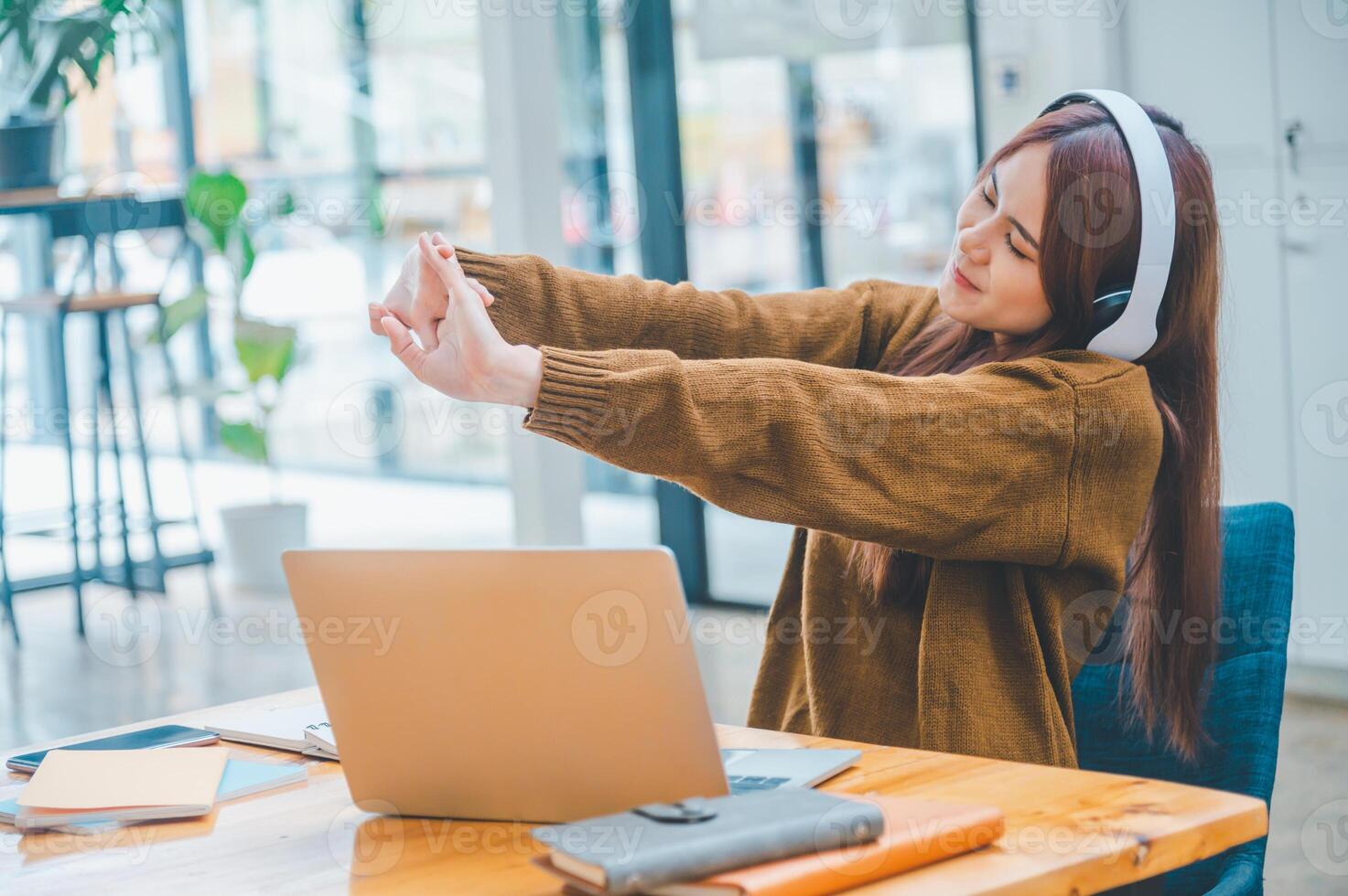 young student wearing headphones pretends to relieve fatigue during long online classes, distance learning, and keeps up to date on the global coronavirus pandemic. photo