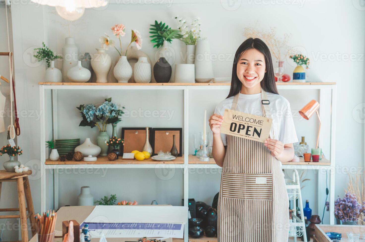 Smiling online small business owner holding a sign saying Open and happily working at a courier business offering orders and products to customers.Online retailer - online shopping. photo