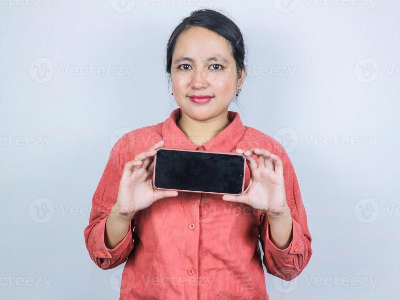 Beautiful Asian business woman showing smartphone mockup of blank screen on white background. photo