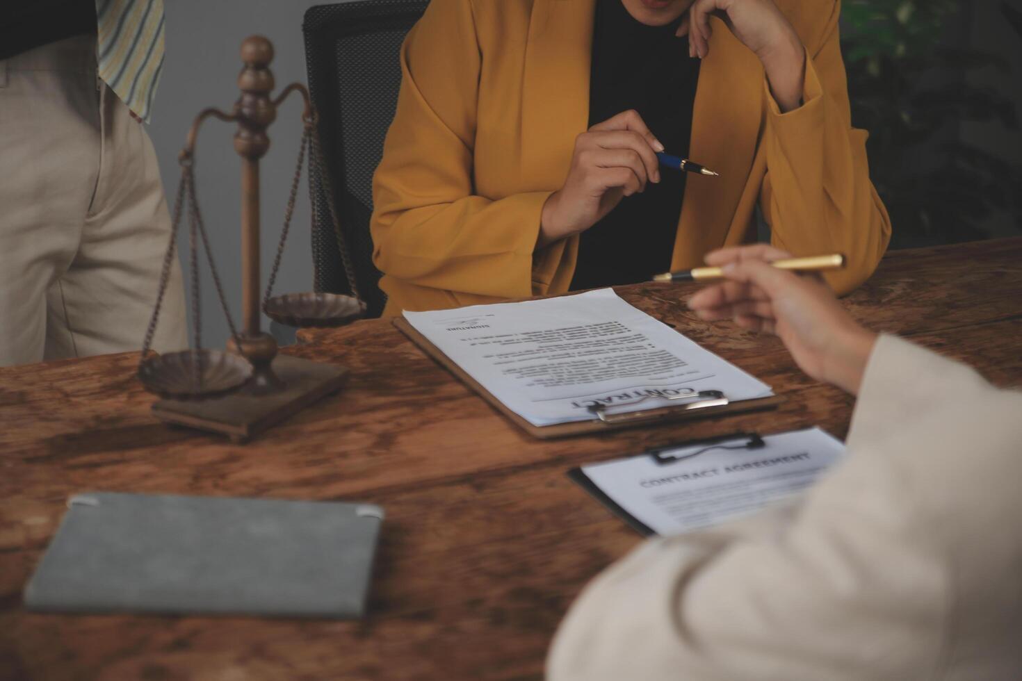 Business and lawyers discussing contract papers with brass scale on desk in office. Law, legal services, advice, justice and law concept picture with film grain effect photo