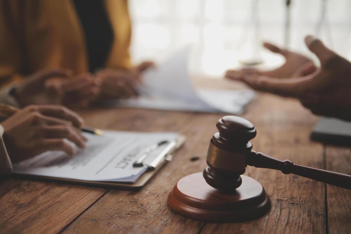 Business and lawyers discussing contract papers with brass scale on desk in office. Law, legal services, advice, justice and law concept picture with film grain effect photo
