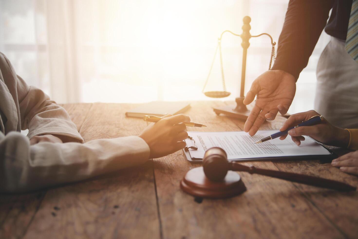 Business and lawyers discussing contract papers with brass scale on desk in office. Law, legal services, advice, justice and law concept picture with film grain effect photo