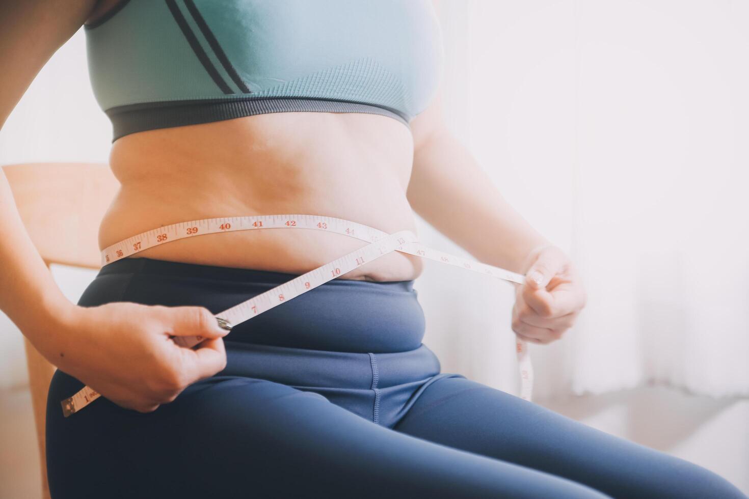 fat woman, fat belly, chubby, obese woman hand holding excessive belly fat with measure tape, woman diet lifestyle concept photo
