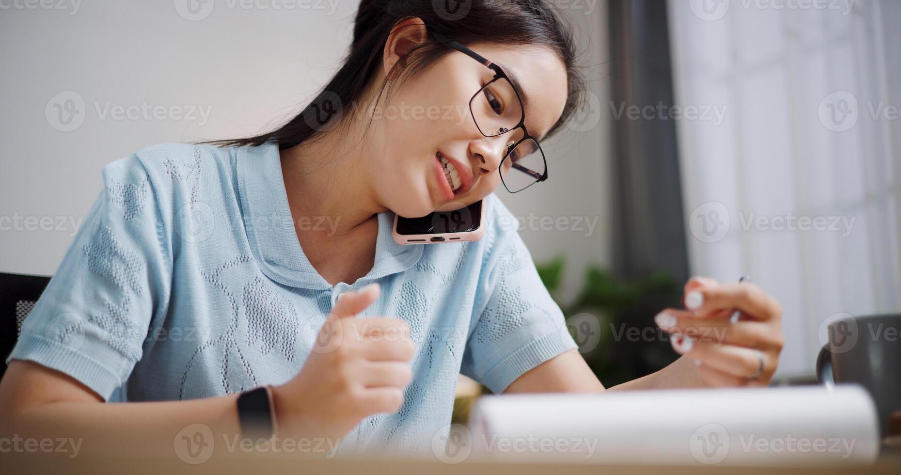 Portrait of Female freelancer sitting at desk explain work to co-workers via mobile phone in home office. Working from home photo