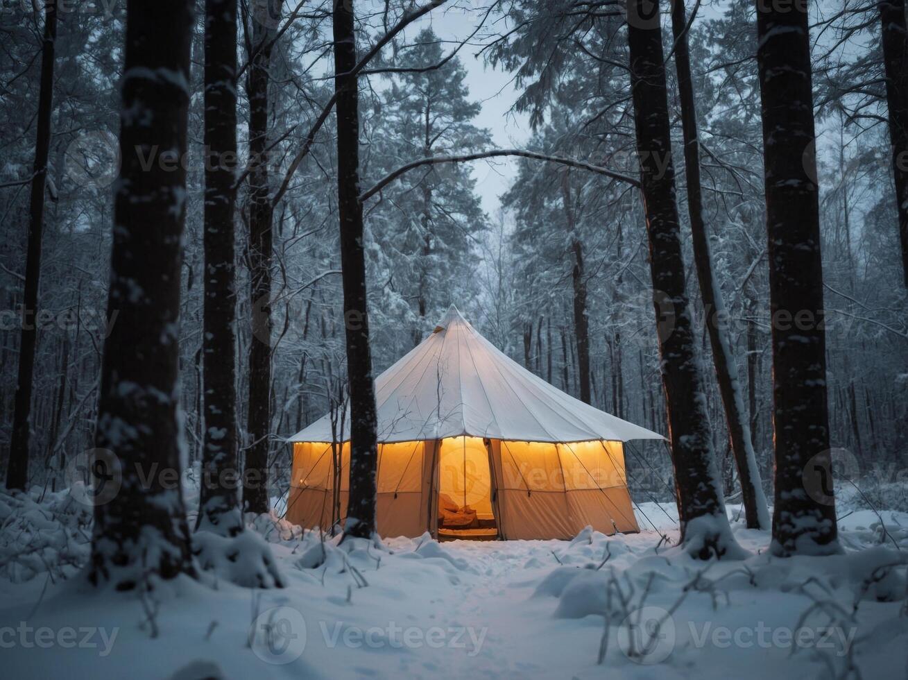 A glowing tent stands out in a serene snow-covered forest. photo