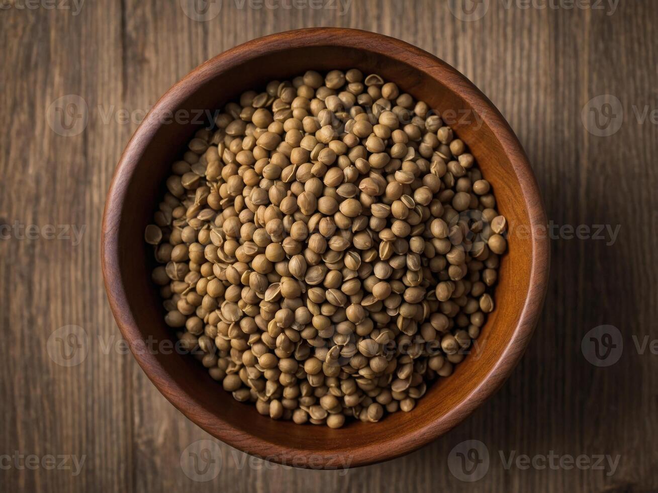 Top view of A wooden bowl filled with Lentils with some scattered around the bowl. photo