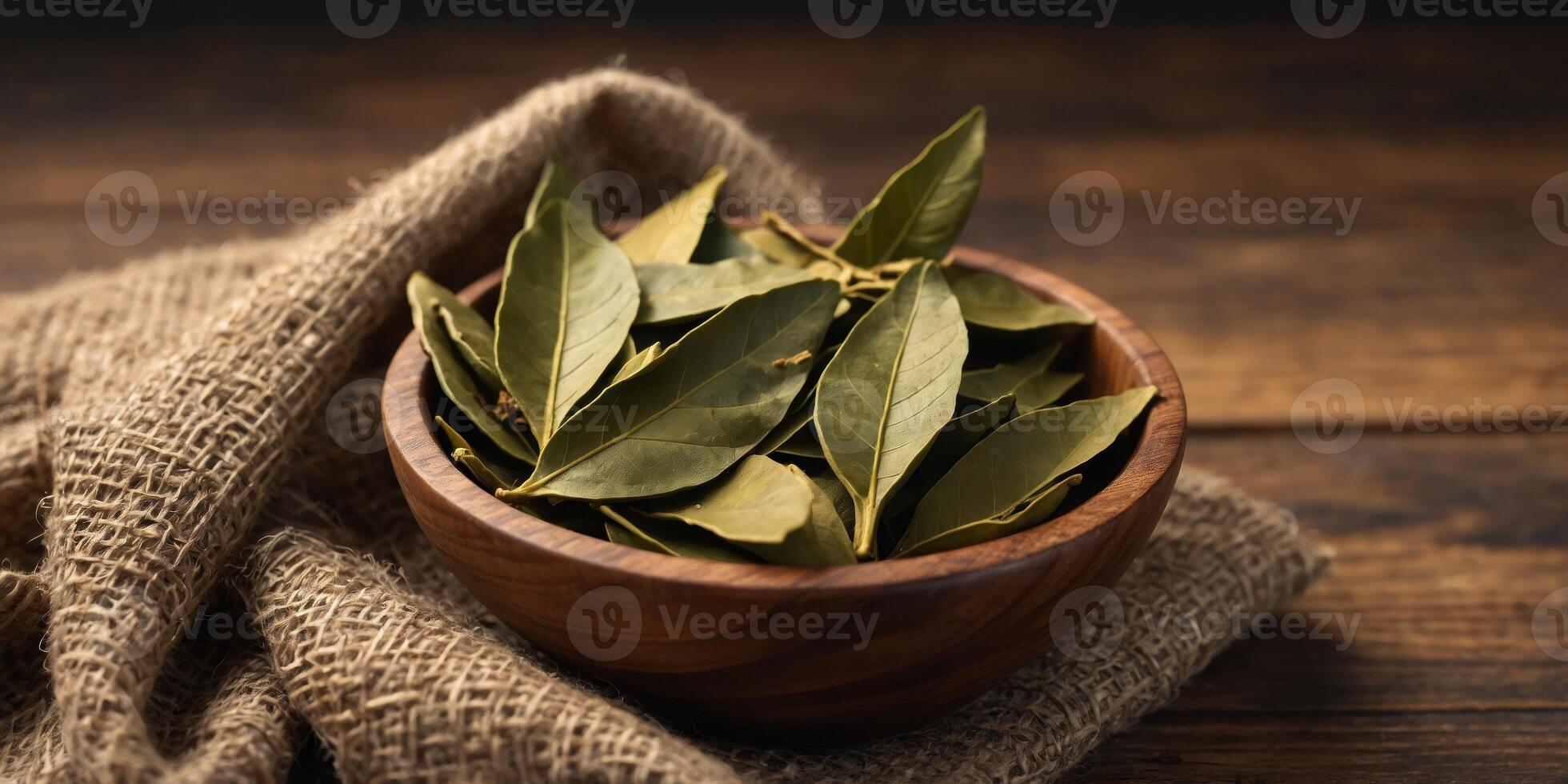 Crushed bay leaf in a wooden cup A whole bay leaf. photo
