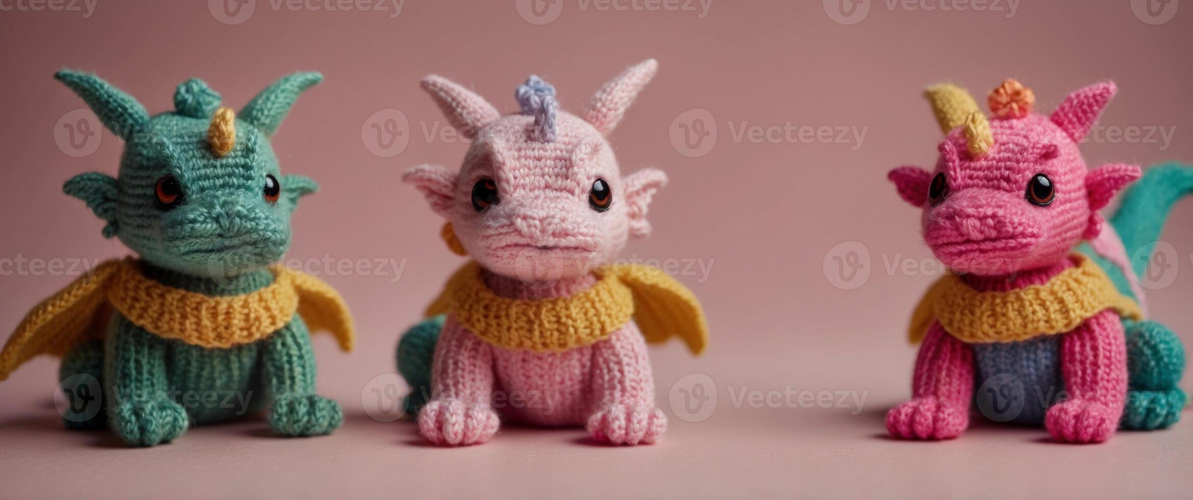 three small knitted dragons on a pink background. photo