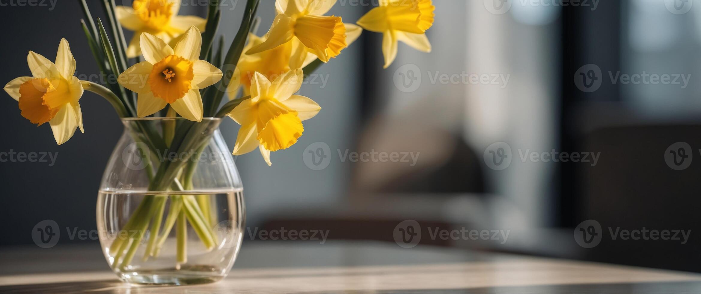 Yellow daffodils in a glass vase standing in a sunny room. photo