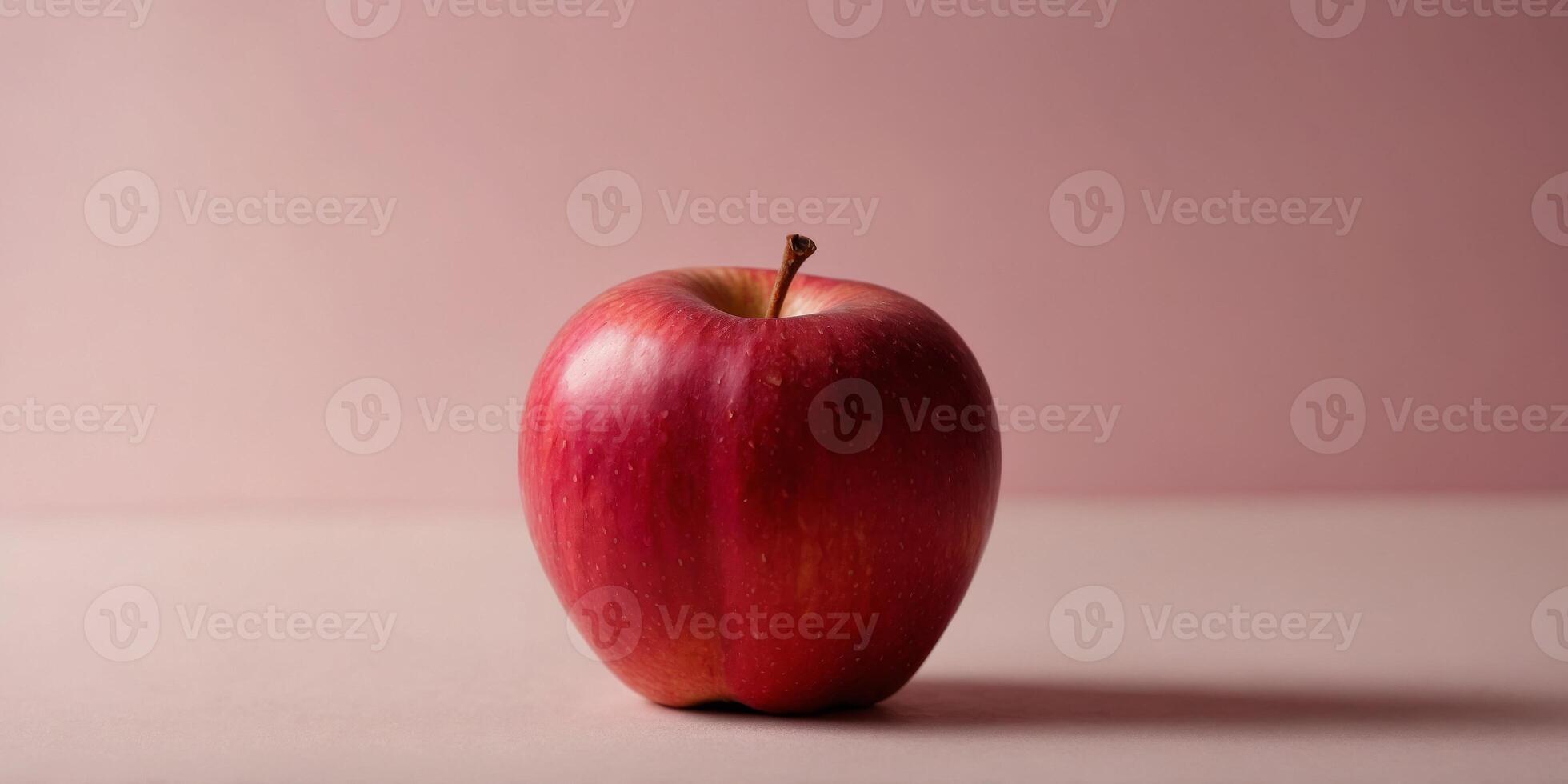 Single red apple in front of pink background. photo