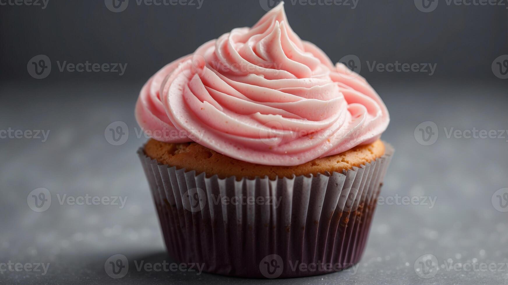 Delicious Pink Frosted Cupcake With Swirls of Creamy Icing on a Gray Background. photo