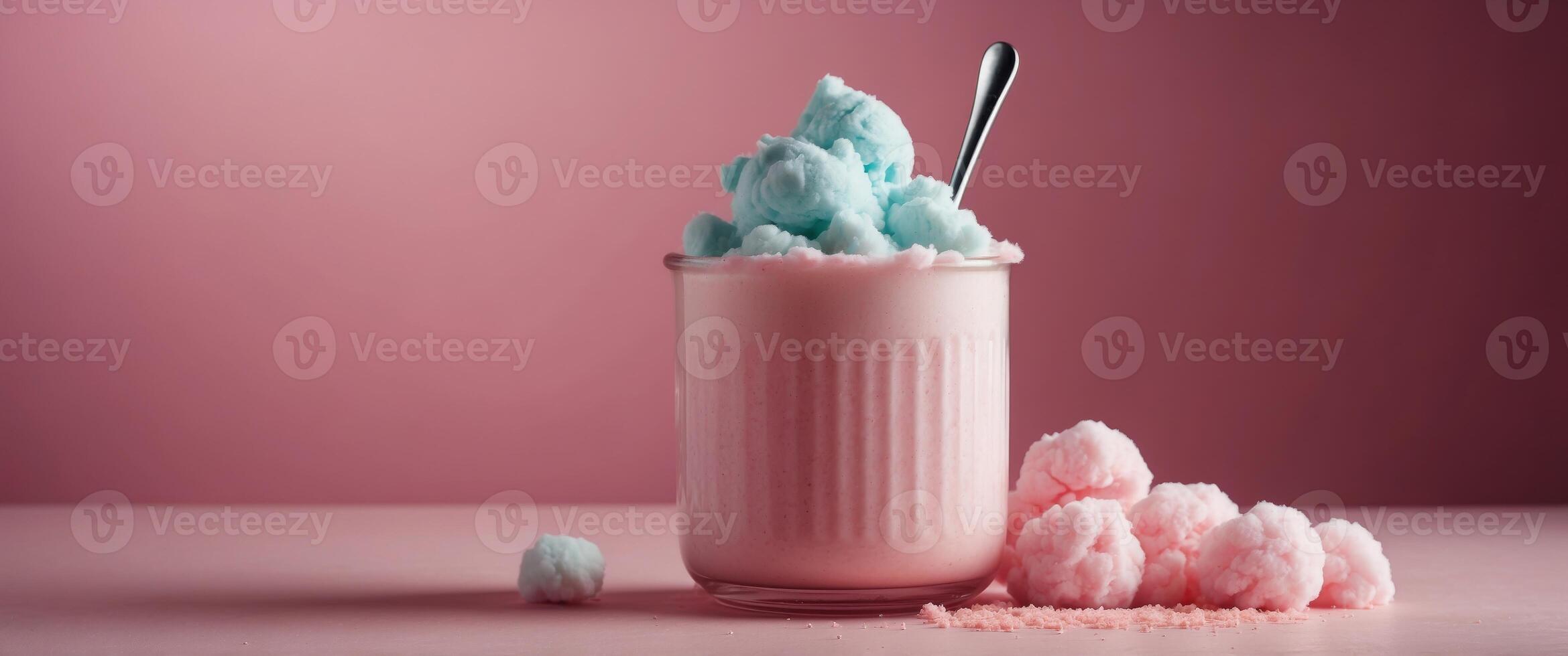 Milkshake in a glass jar covered with a cotton candy on pink background. photo