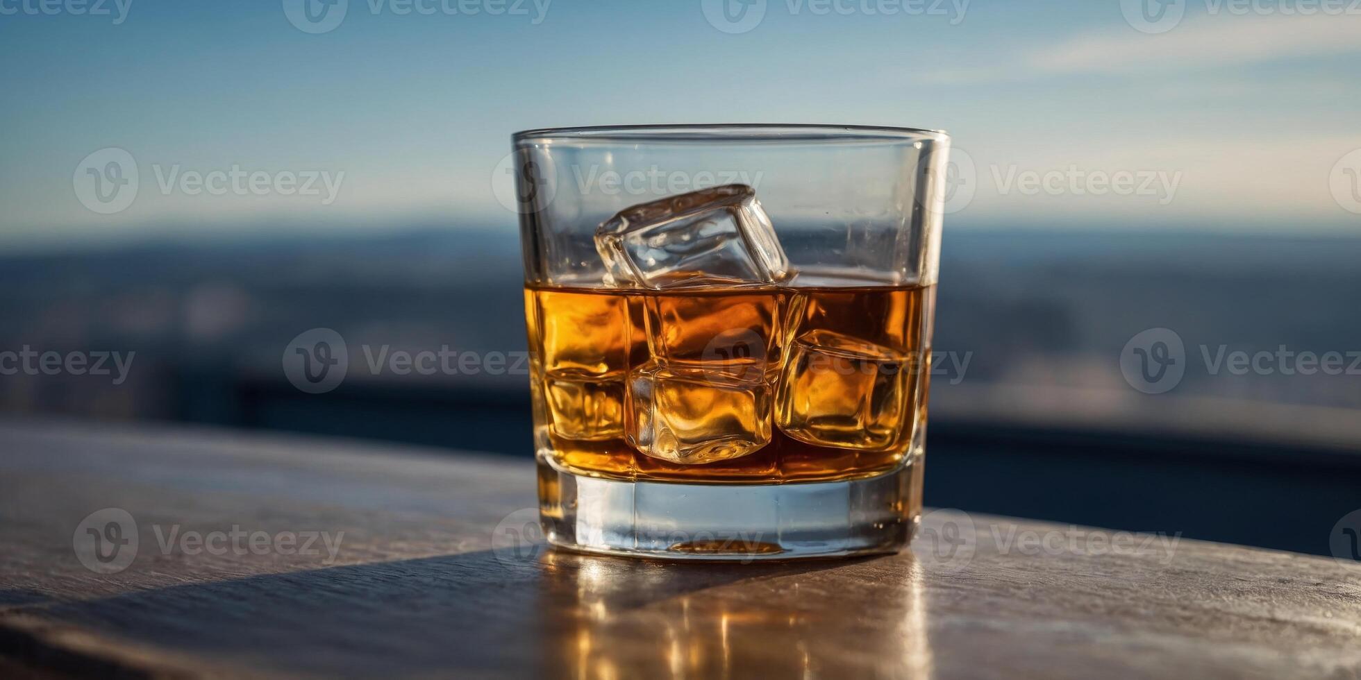 A glass of whiskey is sitting on a table with a blue sky in the background. photo