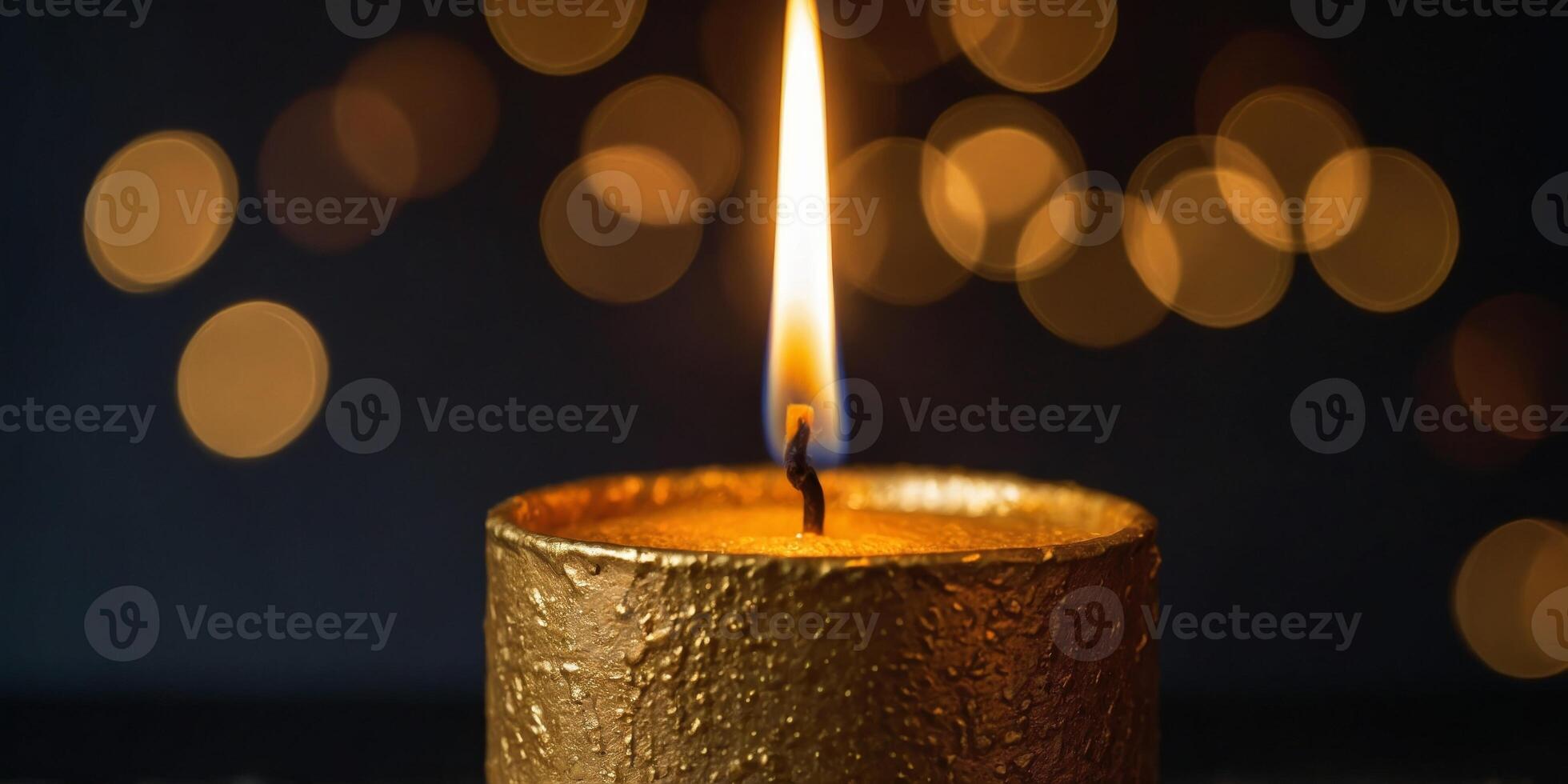 A gold candle with a flame is lit on a dark surface. photo