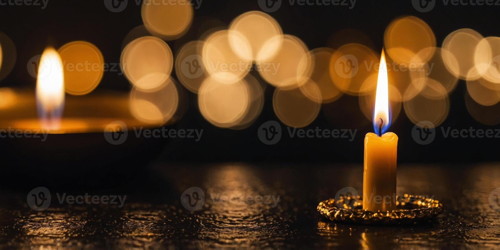 A gold candle with a flame is lit on a dark surface. photo